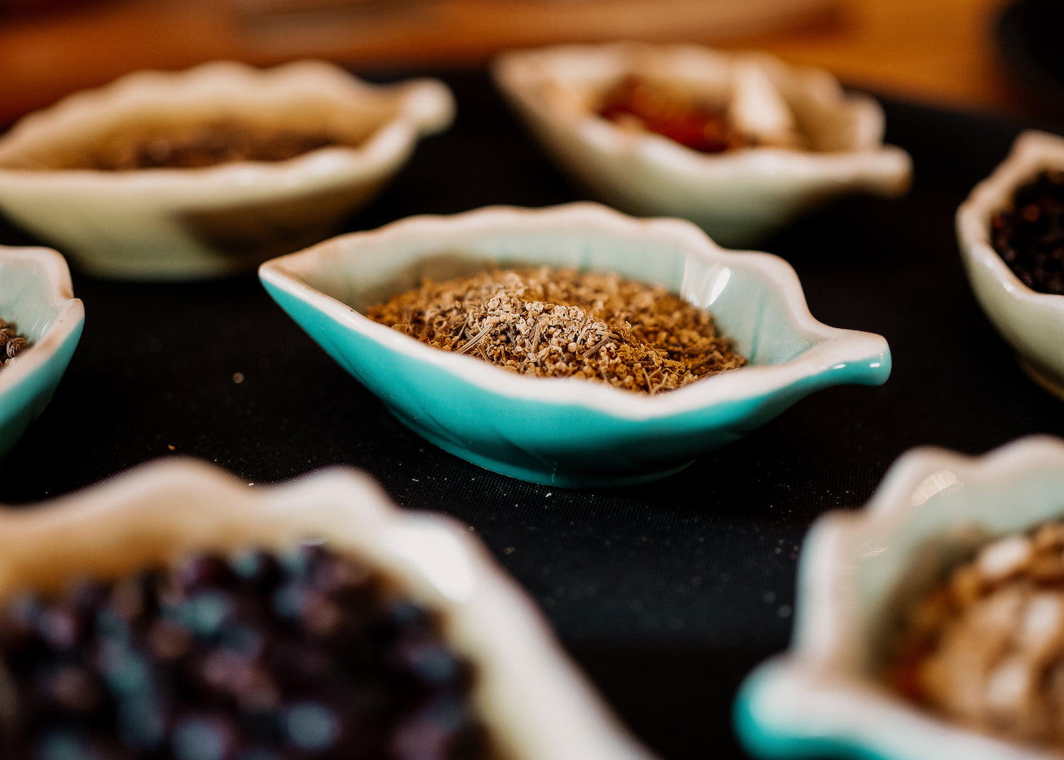 Close up of dried gin botanicals laid in leaf-shape blue dishes on a tray