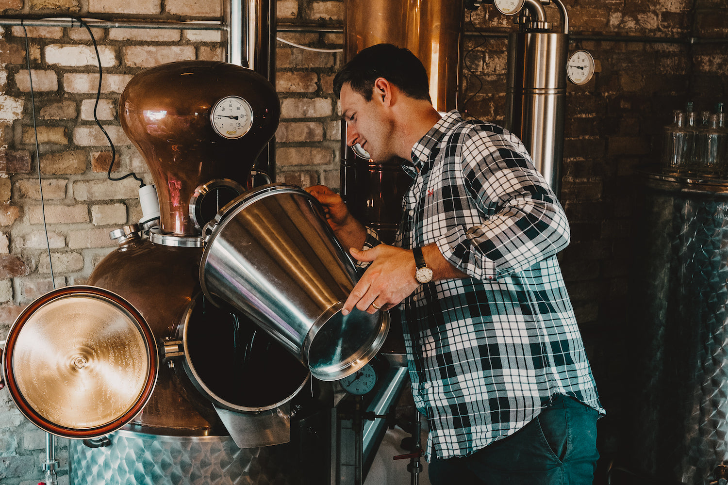 Rupert with the copper still, pouring water into the opening from a steel bucket