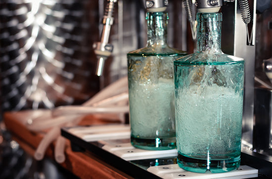 Roundwood Blue bottles lined up on bottle machine, half-filled with gin